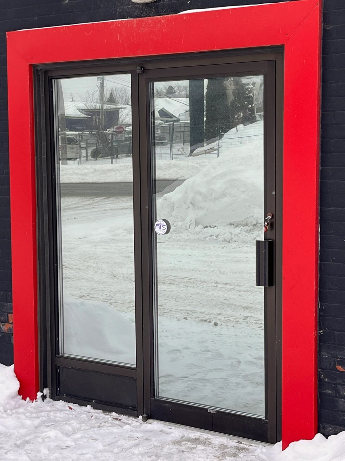 Red-framed commercial entrance door with security film