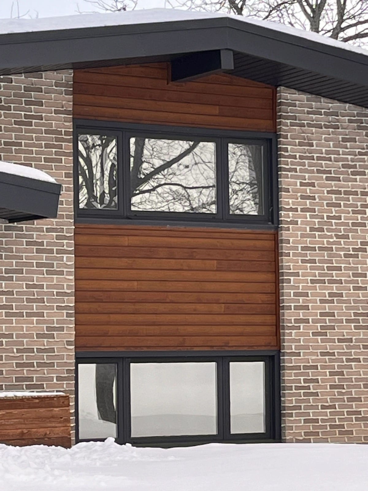 Modern brick home with dark tinted windows in winter